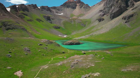 epic cinematic aerial drone high elevation dreamy heavenly island lake silverton ice lake basin unreal caribbean aqua blue silverton colorado lush green summer snow melting rocky mountains slow reveal