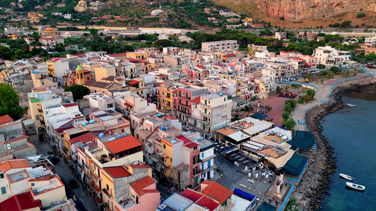 Vista aérea ao nascer do sol da pitoresca vila costeira, da margem do porto e da área residencial em Sferracavallo, Palermo, Sicília, Itália, realçada pela quente luz dourada da manhã