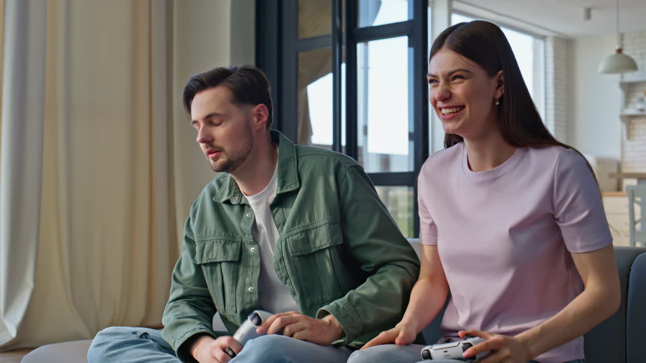 Video gaming couple playing together sitting sofa closeup. Boyfriend losing game