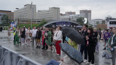 people gathering in a city plaza on a rainy day