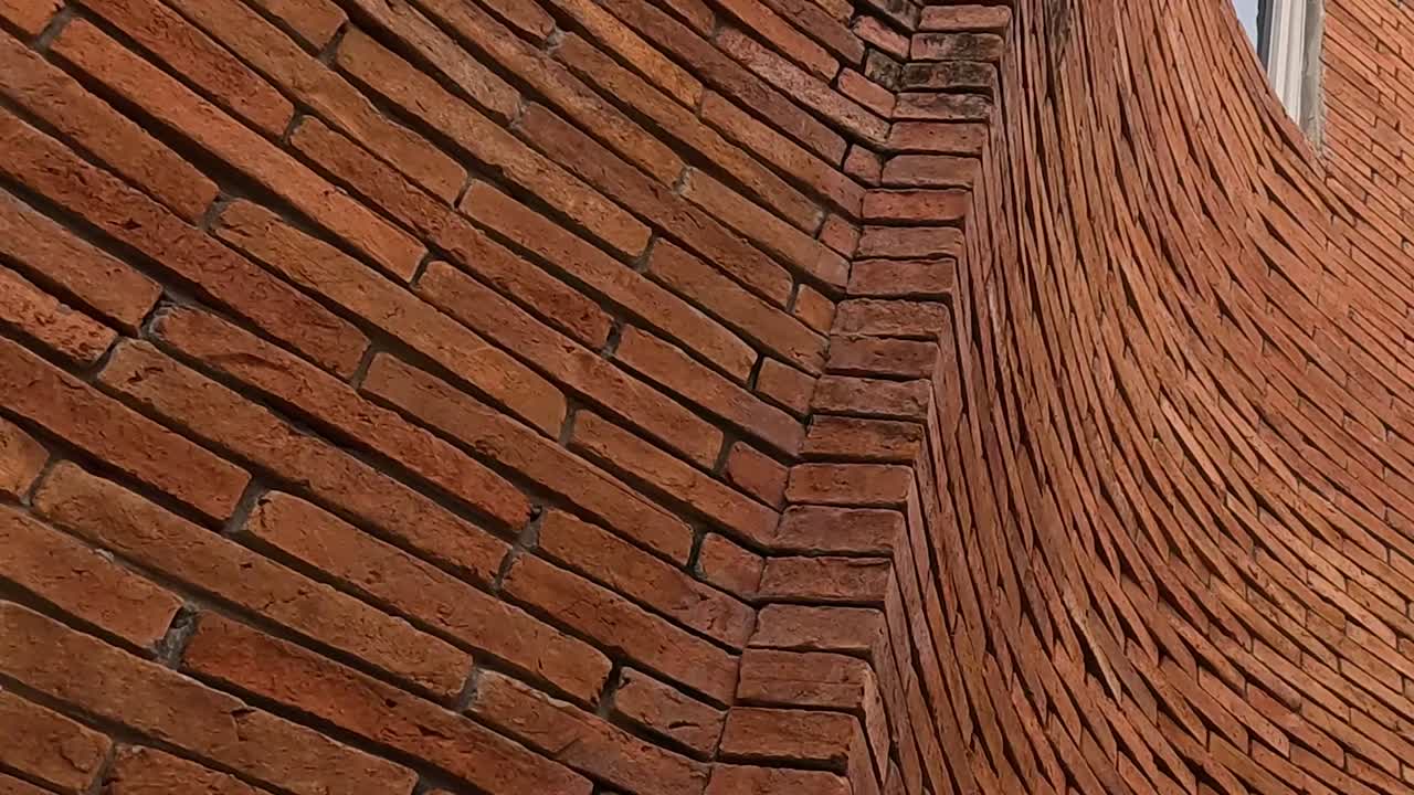 Close-up view of a curved brick wall showcasing detailed masonry and corner angles.