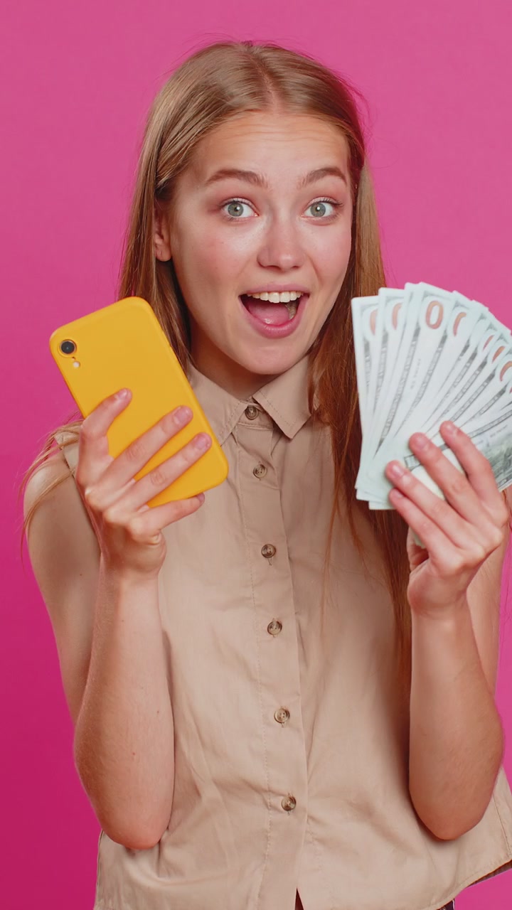 Young woman use smartphone rejoicing win receiving money dollar cash banknotes celebrating success
