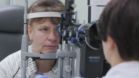 woman doctor is viewing through ophthalmoscope in eyes of patient in ophthalmologic clinic. professional inspection of vision