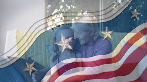 American-flag-design-pattern-against-caucasian-mother-kissing-her-daughter-at-home