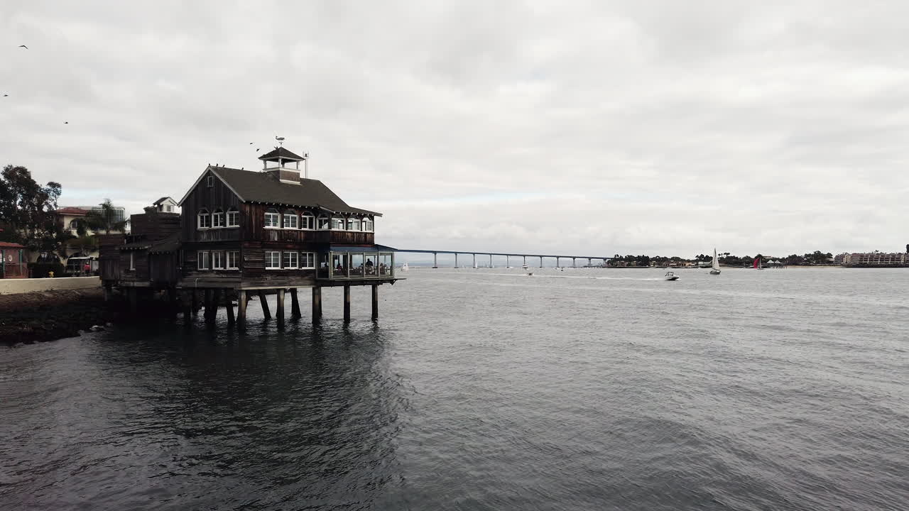 Wooden Harbor House restaurant on stilts above the water at Seaport Village with Coronado Bridge in the background