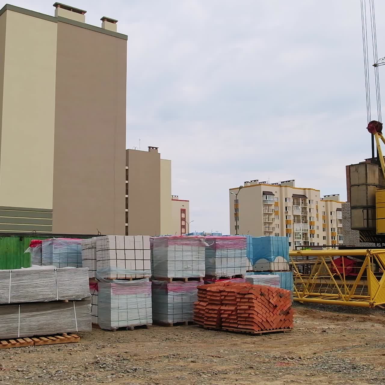 The construction of a new residential area of multi-storied blocks of flats. Crane and building materials at the backdrop of unfinished houses