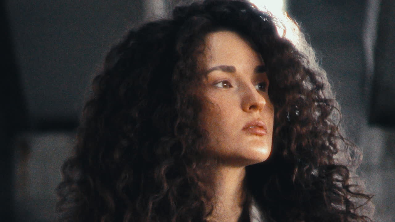 Young Woman in Fluffy Jacket Looking Around under Concrete Urban Overpass