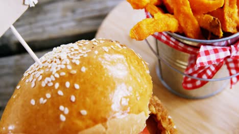 hamburguesa francesa con papas fritas en el cubo mantenido en la mesa