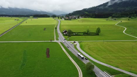 Alpine-Serenity:-4K-Aerial-Drone-Shot-of-Foggy-Drive-from-Graz-to-Hallstatt,-Cars-Wind-Through-Austrian-Countryside-with-perfectly-mowed-green-fields-and-Breathtaking-Alps-Panorama