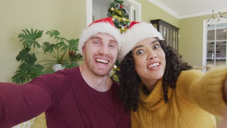 Happy-diverse-female-friends-in-santa-hats-making-christmas-video-call,-smiling-and-holding-device