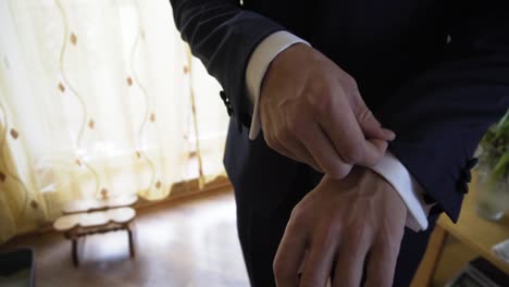 close up of wedding groom slowly adjusting his dark suit with hands