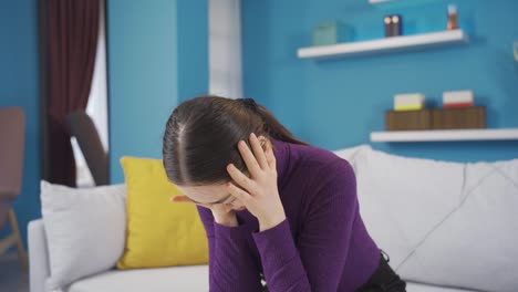 una mujer asiática se vuelve loca de repente mientras está sentada sola en la sala de estar.