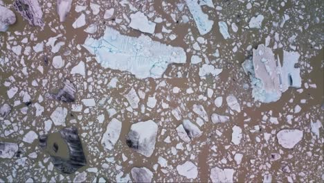 icebergs floating in brown muddy glacier lagoon in iceland