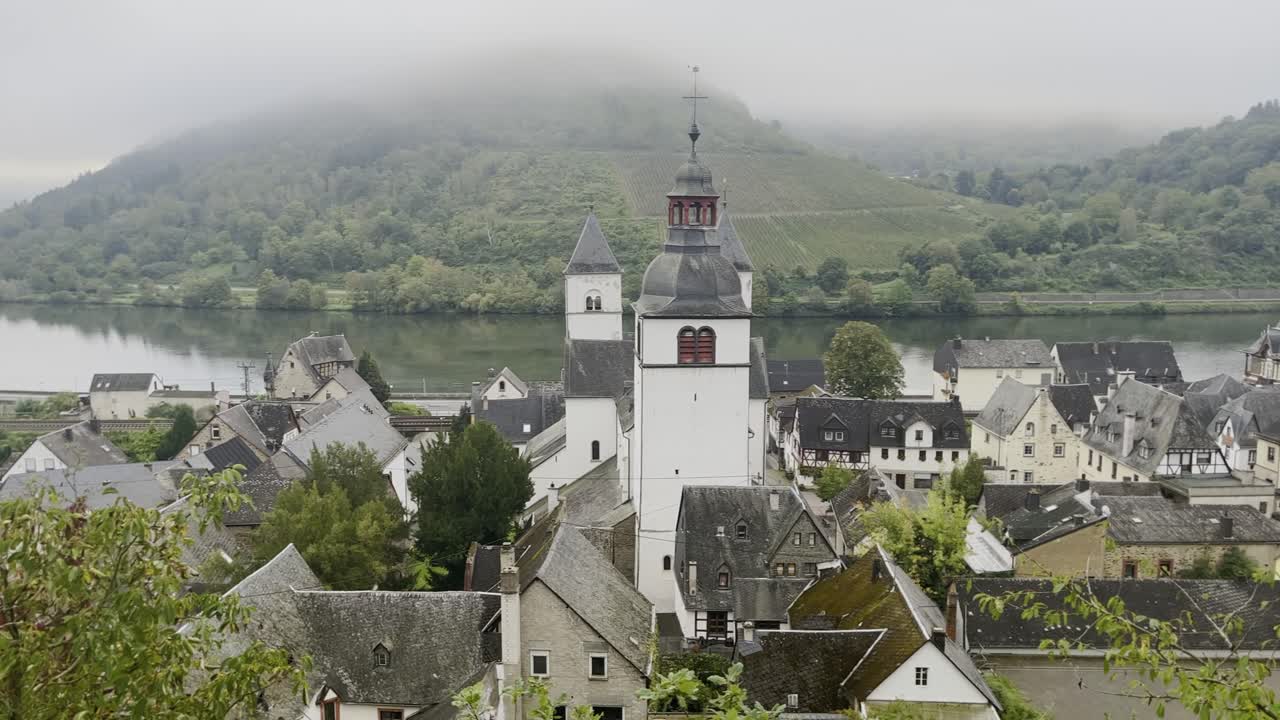 Small German town on a river in a valley in the fog between two wooded hills with a lot of thick fog, on the Moosel in Germany