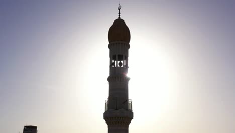 minaret silhouette against a bright sunlit sky