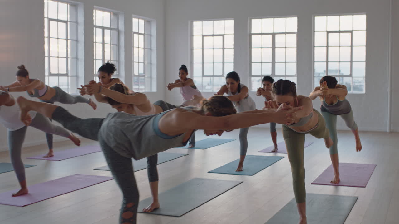 전사 포즈를 연습하는 건강한 여성의 요가 수업은 일출 시 그룹 명상 교육 운동 자세를 이끄는 피트니스 스튜디오 강사에서 운동을 즐기고 있습니다.