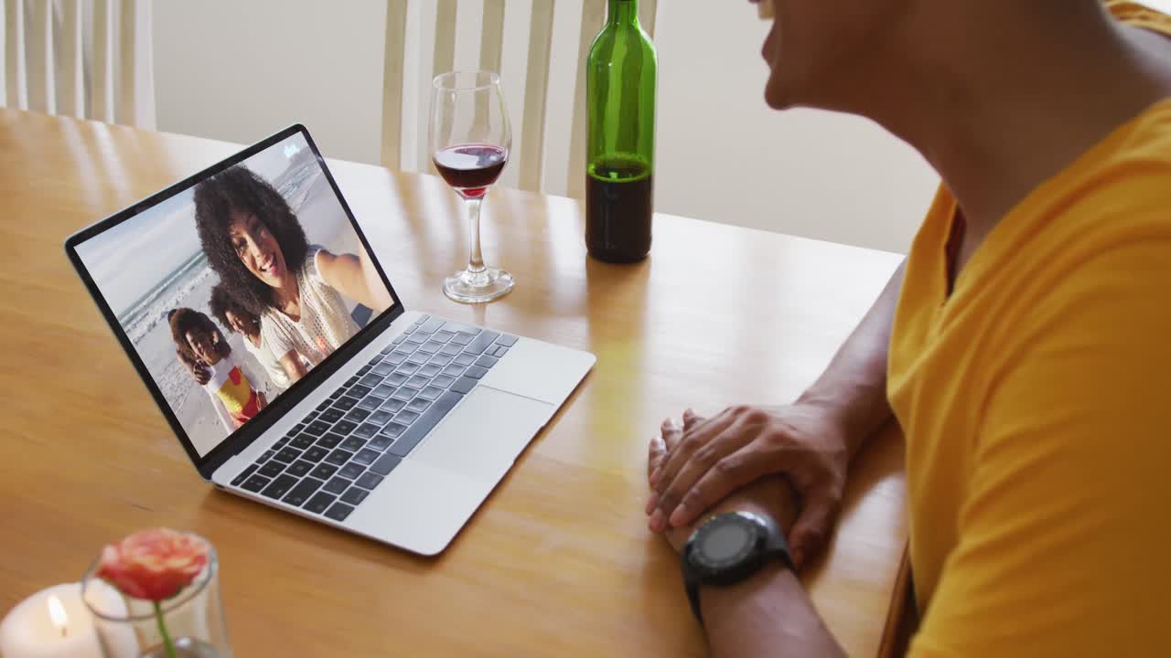 Mid section of african american man talking on video call on laptop at home