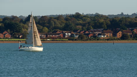 small sailboat sails into and out of frame at solent southampton with weston in background