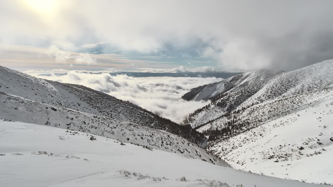 nubes rodando sobre el valle cubierto de nieve entre altos picos alpinos en tatras, eslovaquia