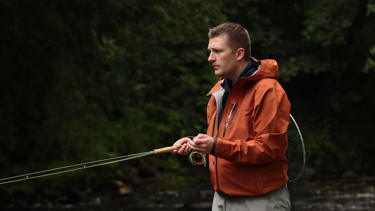 disparo en primer plano de un pescador de mosca caminando y echando en un pequeño arroyo