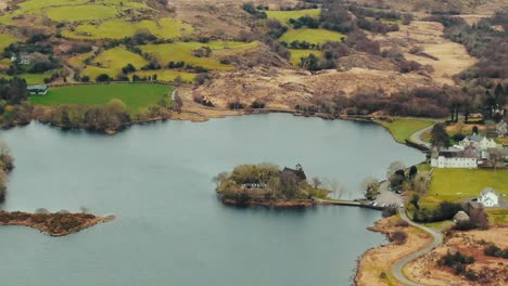 pan out shot of gouganebarra lake and surrounding hills and st. finbarr's oratory island in ireland