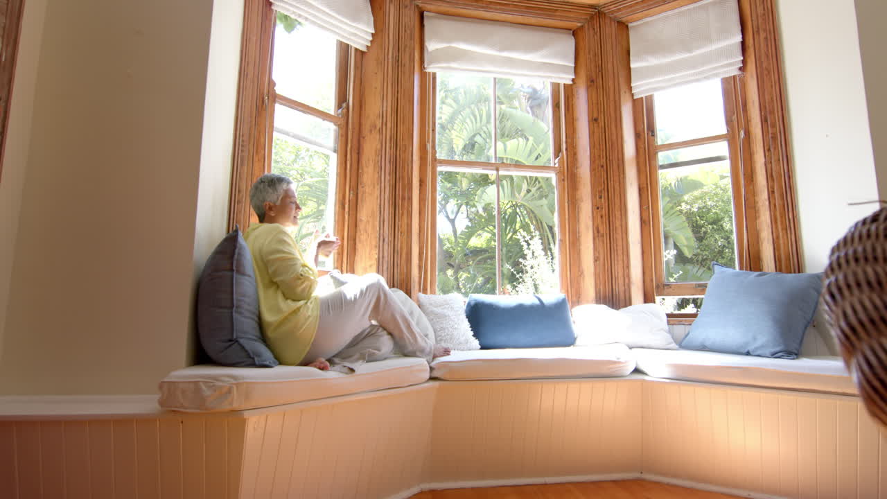 소파에 앉아서 집에서 차를 마시는 행복한 두 인종의 여성, 느린 동작