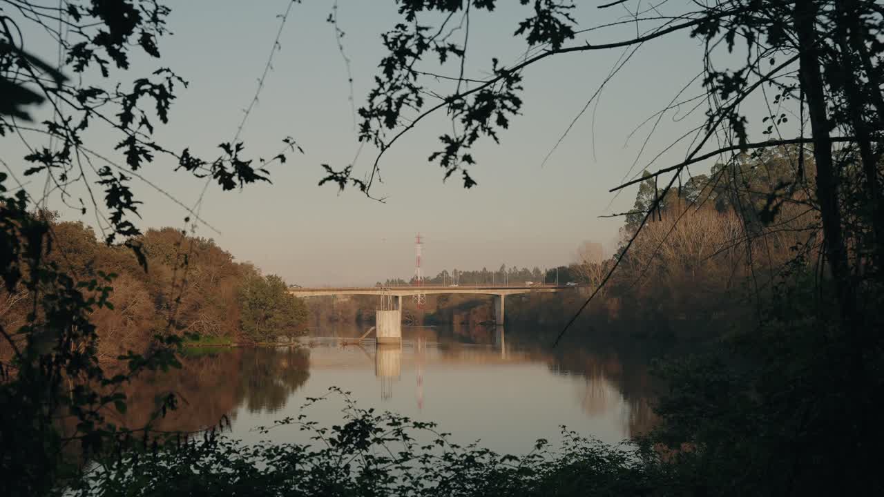 Serene view of a bridge over River Cávado, framed by trees with a calm water reflection