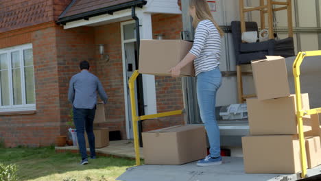 couple unpacking moving in boxes from removal truck