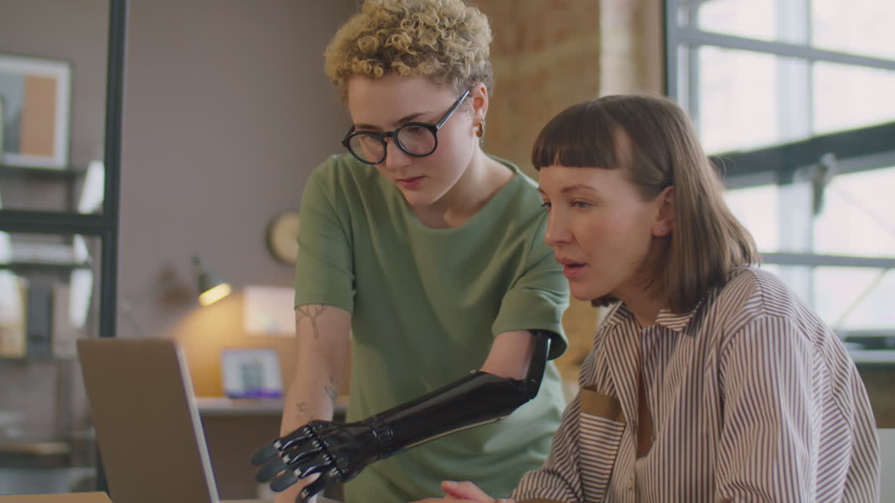 Businesswoman with Prosthetic Arm Helping Colleague in Office