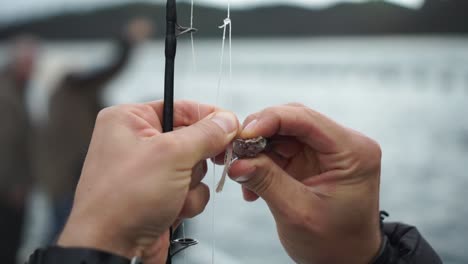 slowmo - man puts bait fish on lure hook - close up