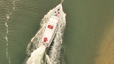 a top down shot over a fishing boat heading out to sea on a cloudy morning