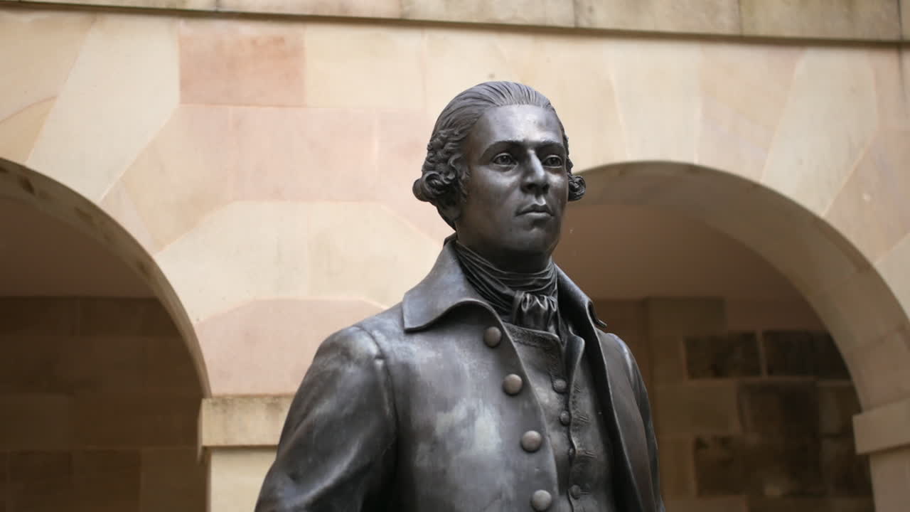 A bronze statue of William Cavendish stands proudly in Buxton, framed by stone archways. The detailed sculpture with British historical significance.