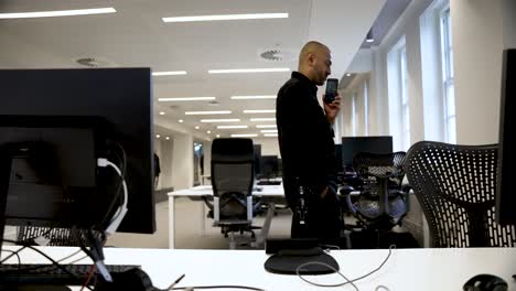 south asian office worker having an early morning phone call while pacing in an empty office