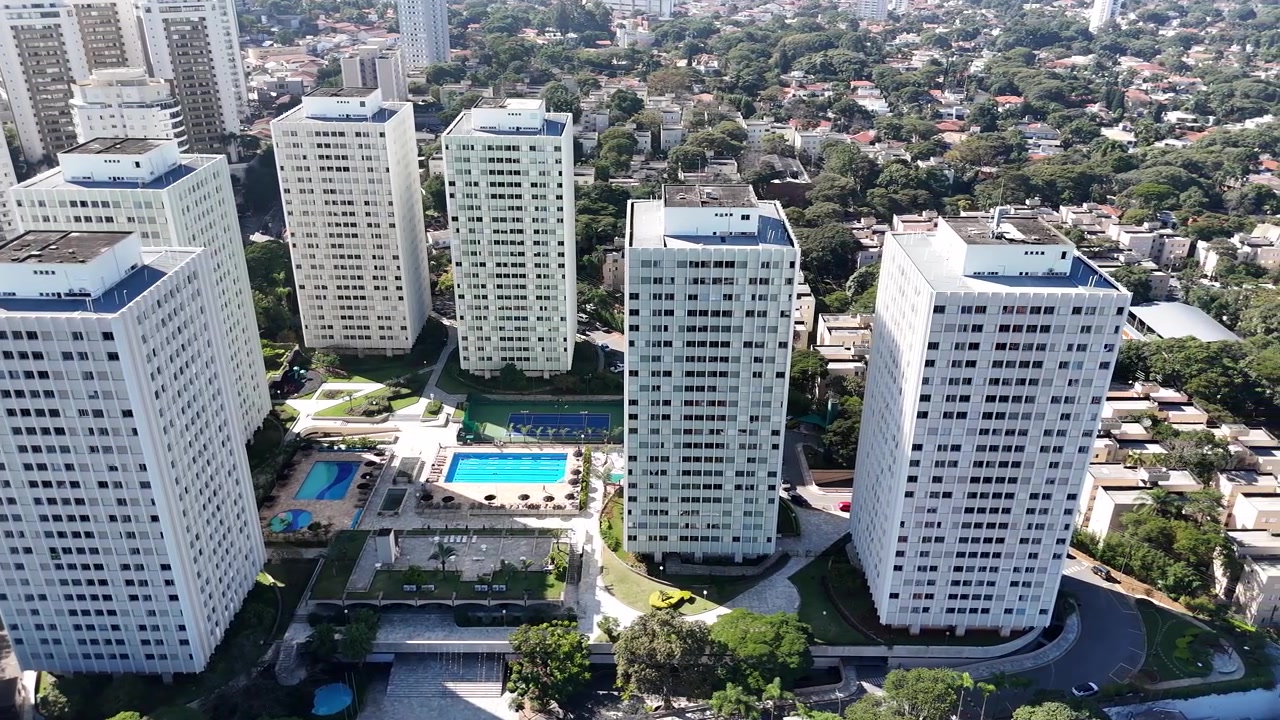 Toma aérea lateral con dron sobre un barrio de lujo en São Paulo, mostrando edificios residenciales de lujo y una zona residencial modesta lado a lado, cerca del Parque Villa-Lobos.
