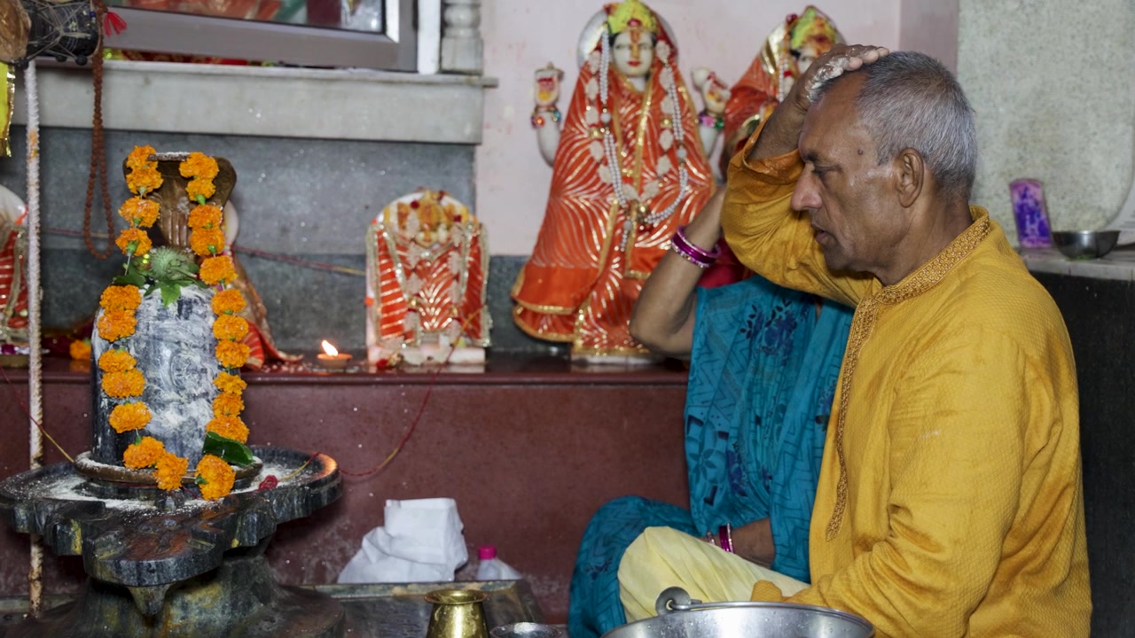 Devoto indù che riceve benedizioni sacre durante una cerimonia di culto nel tempio di Lord Shiva.