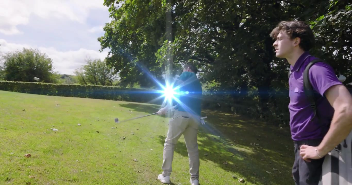 Golfista anziano che avanza sul fairway del campo da golf, eseguendo uno swing con il ferro mentre lancia la palla verso il green.