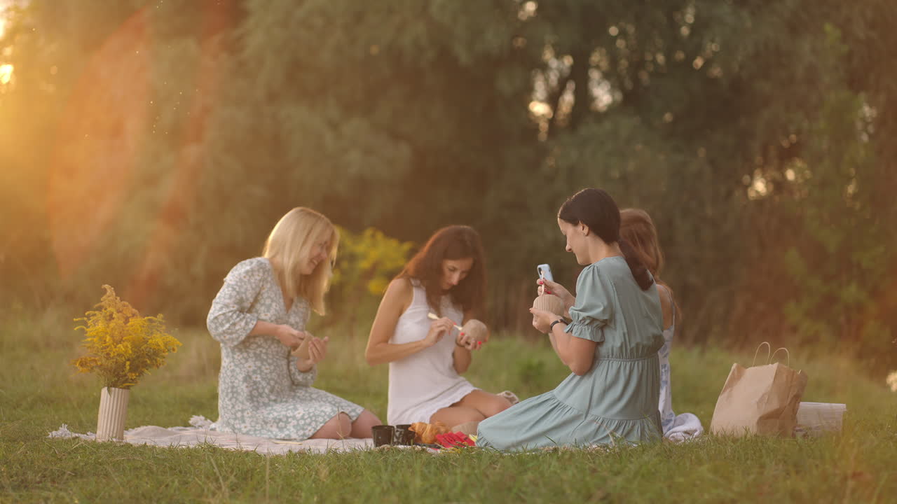 저녁에 해가 지는 야외에서 자연 속의 한 무리의 젊은 여성들이 도구를 사용하여 점토에서 조각을 하고 제품을 장식하고 의사소통하고 인상을 공유하고 결과에 기 ⁇ 합니다.