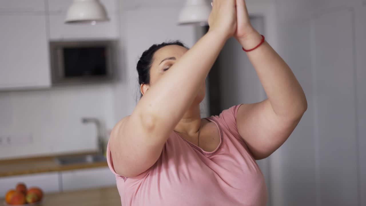 Giovane donna attraente taglia forte che pratica yoga, con le mani in posizione Namaste.