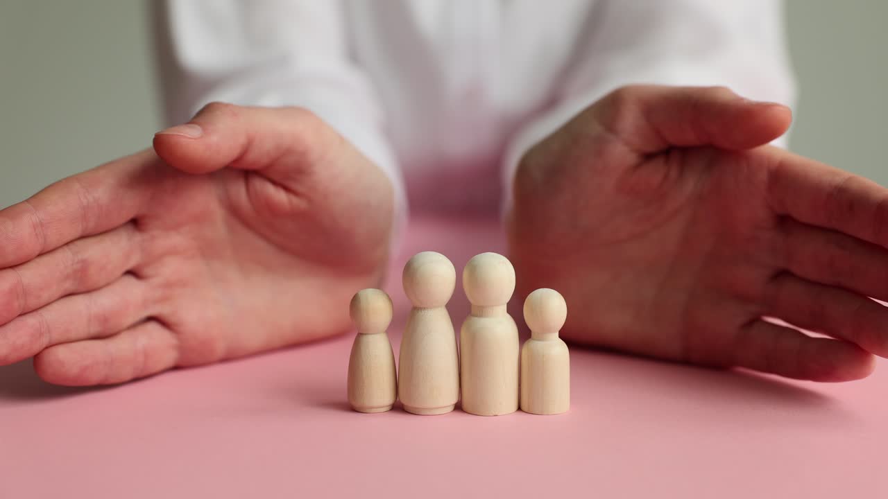 Woman covers wooden figurines with palms on pink table