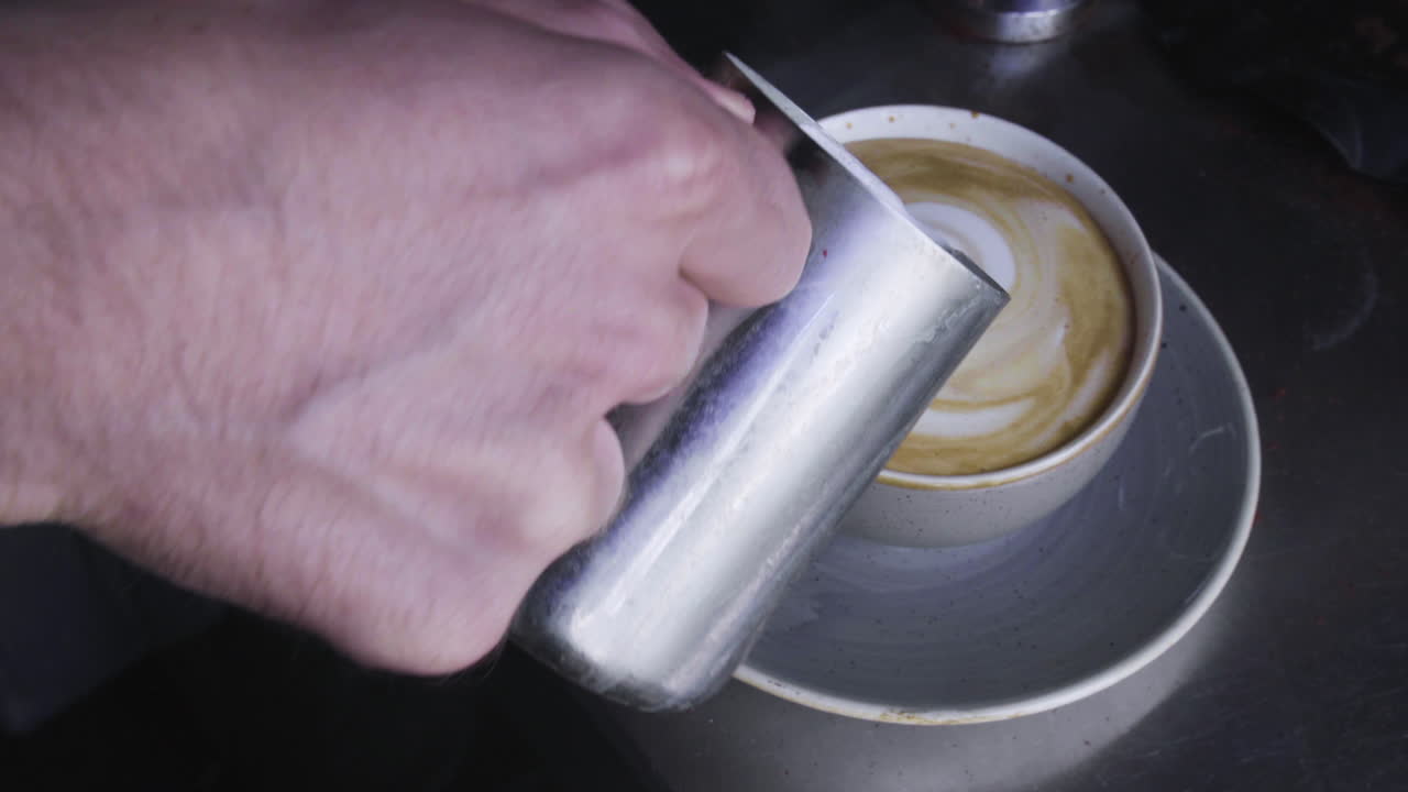4K Barista pouring milk into coffee, latte art