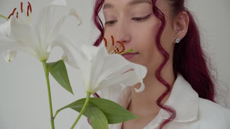 pretty millennial hipster girl with pink hair smelling white madonna lily flowers