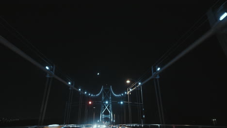 wide low angle shot of lions gate bridge suspension ropes and tower at night, vancouver, canada
