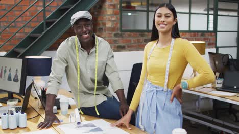portrait of happy diverse fashion designers wearing the tape measures at office