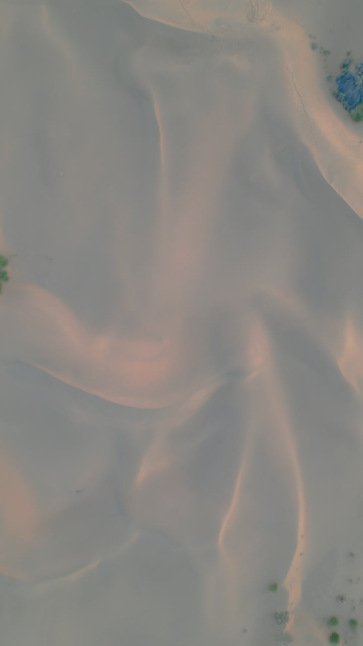 An aerial drone shot of the sand dunes in Jaisalmer, Rajasthan, showcasing the rippling patterns and serene beauty of the Thar Desert India 4K