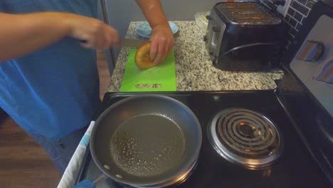 single man making breakfast in his bachelor pad frying up eggs spam and making toast