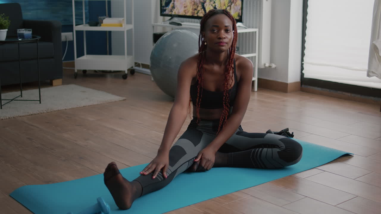 Flexible fit black woman doing stretching routine on yoga map