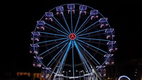 ferries wheel illuminated by neon colorful lights rotating on center of dark sky background