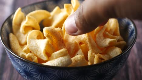 bowl with tasty potato chips on wooden background