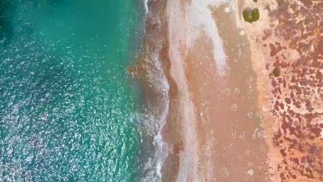 Aerial-view-looking-straight-down-on-the-sparkling-sea-and-beach-waves-of-Paphos-Cyprus