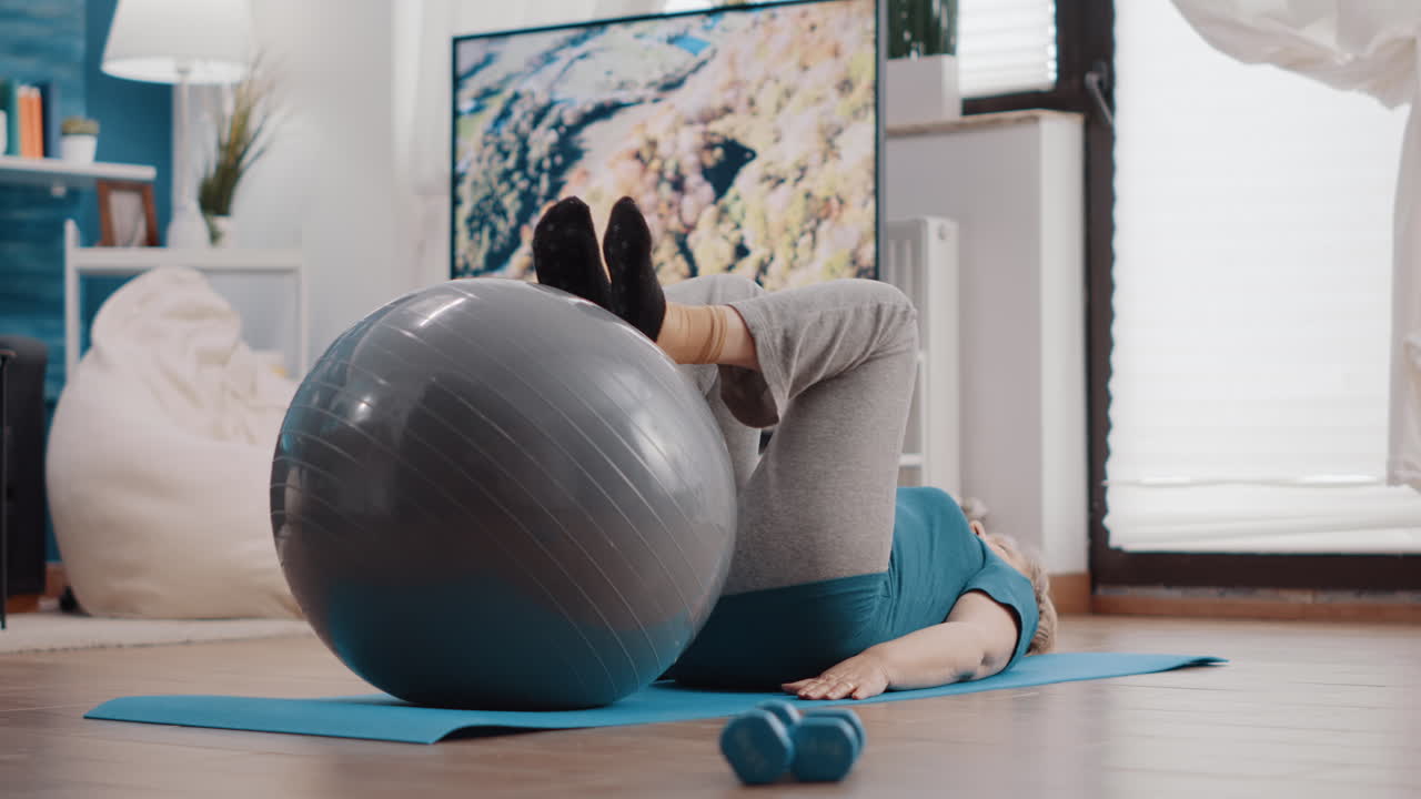 Aged person using fitness toning ball to train muscles